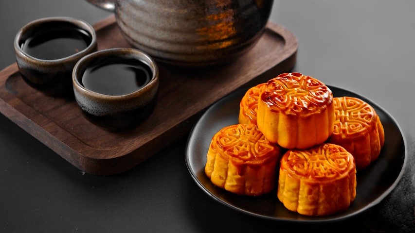 mooncakes in a plate and a pot of tea and mugs
