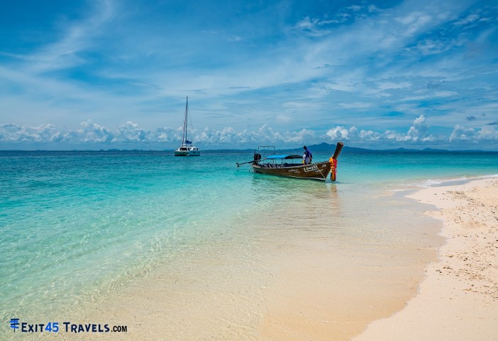 long tail boat on a white sand beach