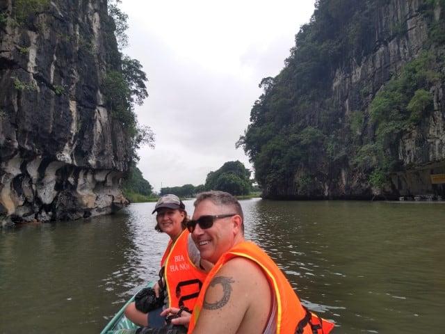 man and woman sitting on a boat with karst mountains in background on a tam coc boat tour